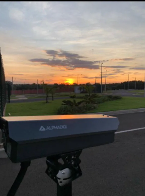 Câmera de leitura de placas (LPR) instalada na entrada de um condomínio ao pôr do sol